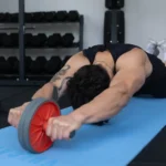 Person using an ab roller on a blue mat for core strengthening exercises in a gym setting. Visit waiteandsea.com.au