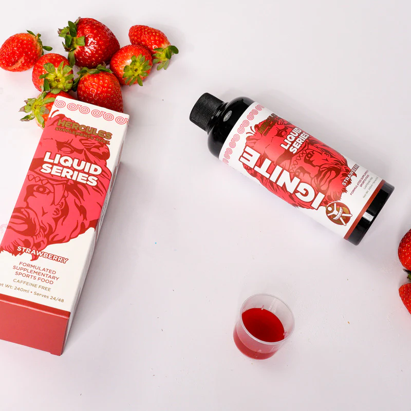 Hercules Ignite Liquid Series Strawberry flavor bottle with box, surrounded by fresh strawberries and a small measuring cup filled with the red liquid.