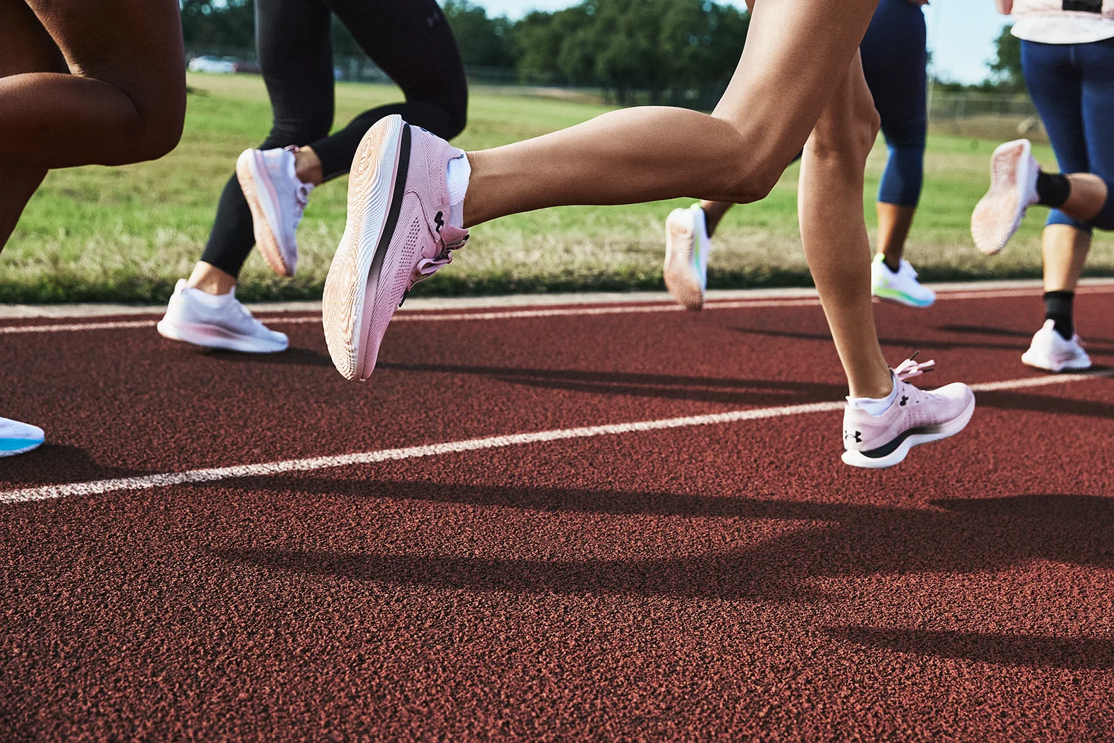 Women running in athletic shoes on a track.