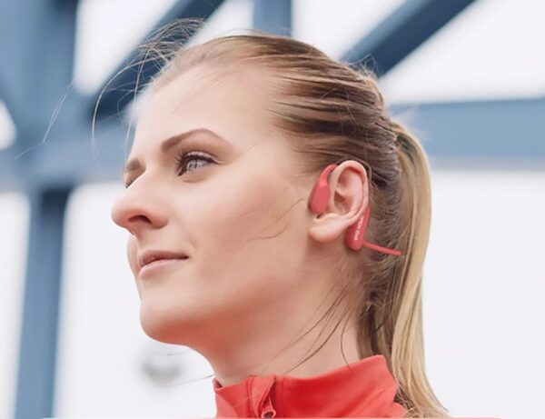 Woman wearing red wireless earphones during outdoor activity, perfect for Health and Fitness enthusiasts. Visit waiteandsea.com.au