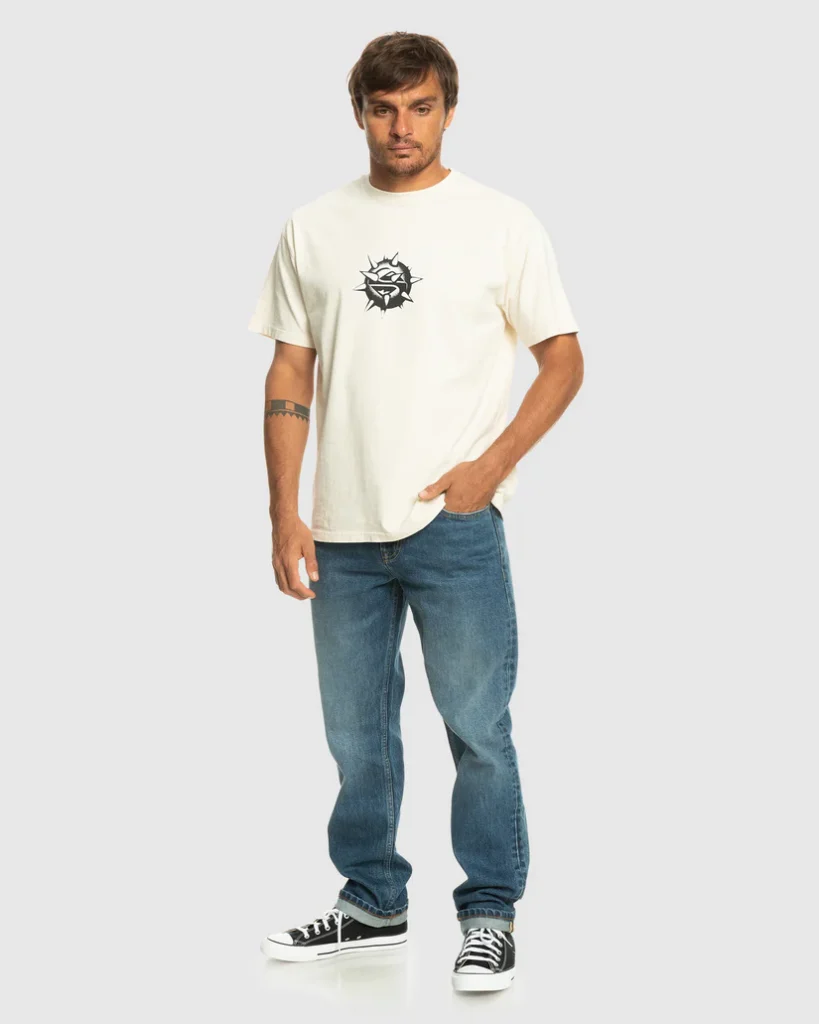 Quiksilver men’s casual outfit featuring a cream t-shirt with a tribal logo and classic blue jeans, paired with black sneakers. Find it at www.waiteandsea.com.au.