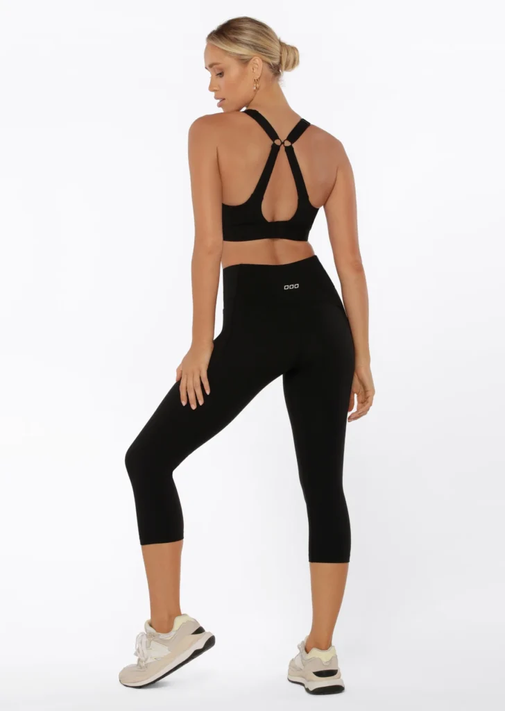 Back view of a woman wearing Lorna Jane black activewear leggings and a stylish sports bra, perfect for health and fitness enthusiasts.