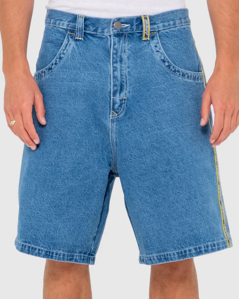 Front view of a man wearing Ghanda blue denim shorts with a yellow side stripe, paired with a white shirt.