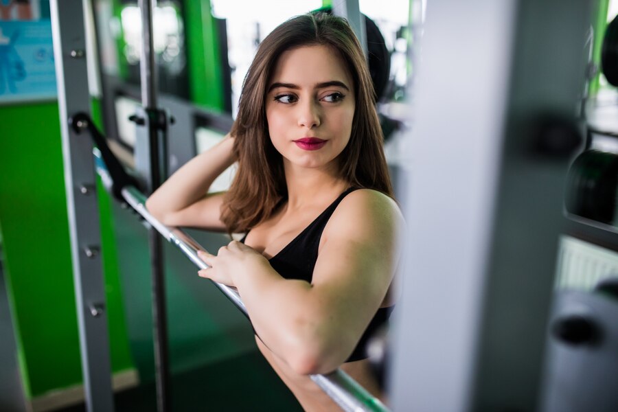 Confident woman resting on gym equipment, showcasing dedication to health and fitness in a modern training environment. Learn more at www.waiteandsea.com.au.