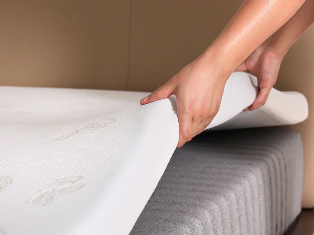 Hands adjusting a Newentor mattress topper on a premium mattress, showcasing superior comfort and support. Perfect for enhancing health and fitness through quality sleep. Explore more at www.waiteandsea.com.au.