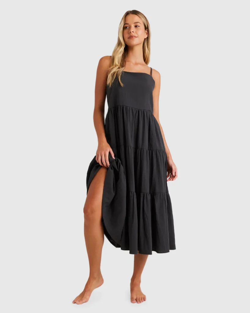 Woman wearing a black tiered midi dress with thin straps, perfect for a relaxed and elegant look.