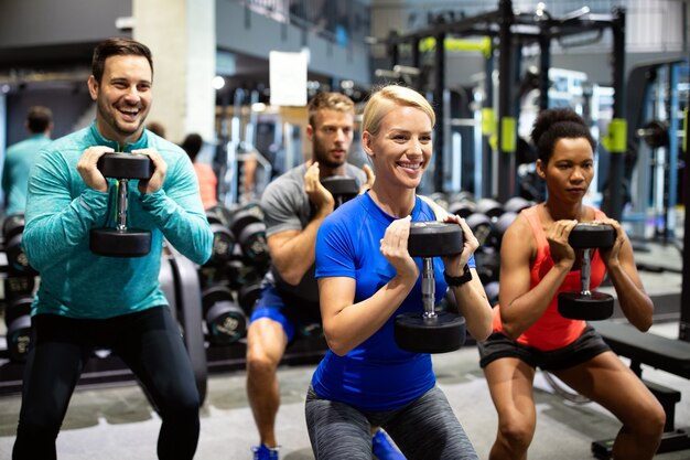 A group of fit individuals performing goblet squats with dumbbells in a modern gym, focusing on strength and endurance. Keywords: health and fitness, group workout, strength training, dumbbell exercises, www.waiteandsea.com.au